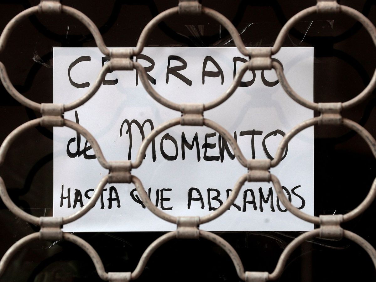 Foto: Detalle de un cartel colgado en la entrada de una tienda con el lema "Cerrado de momento hasta que abramos". (EFE)