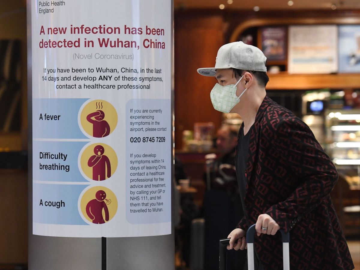 Foto: Un hombre con mascarilla arastra sus maletas por el aeropuerto de Londres-Heathrow. (EFE)