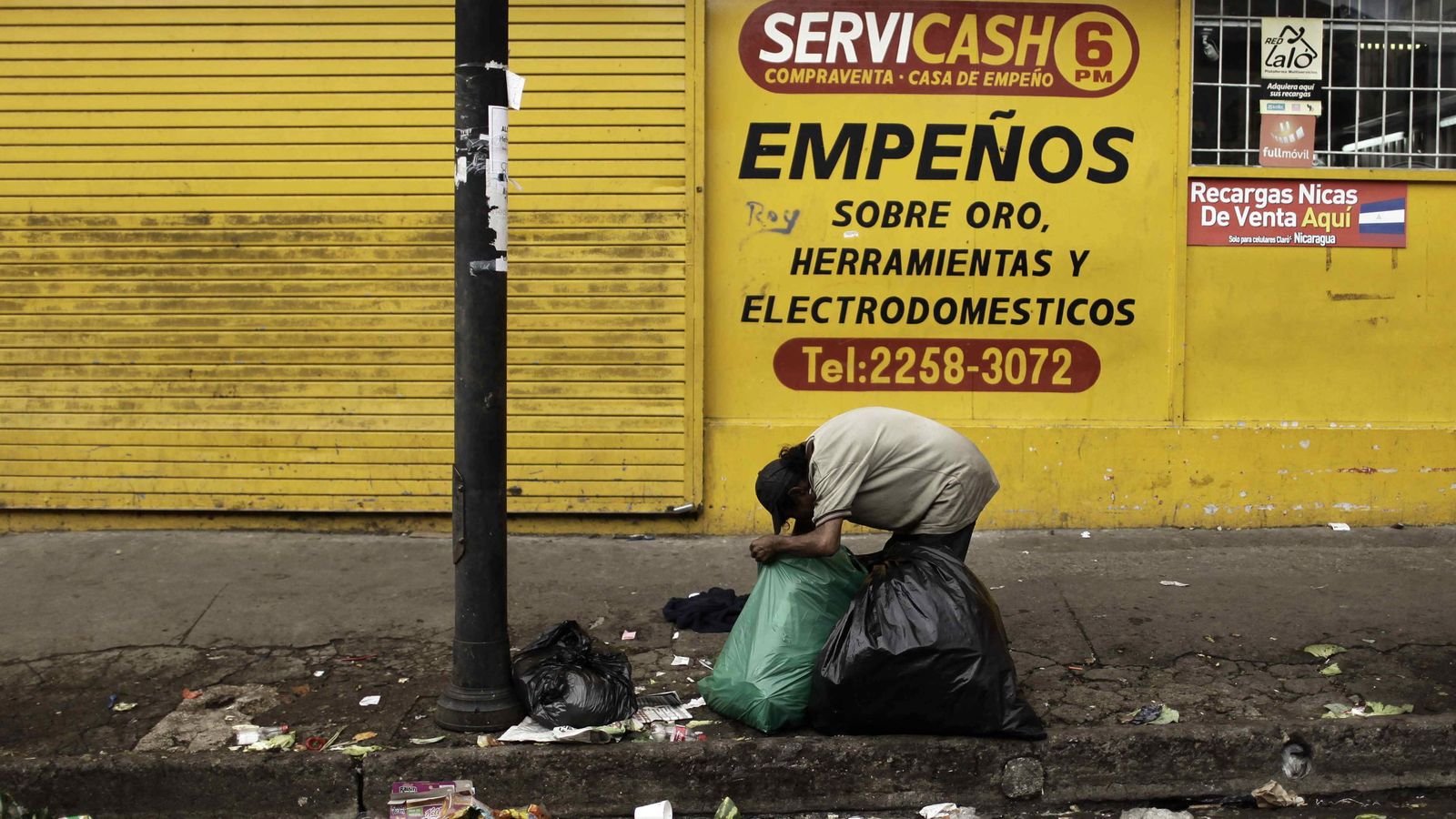 Foto: Un hombre hurga en bolsas de basura en la ciudadela Triángulo de Solidaridad, en San José (Costa Rica). (EFE)