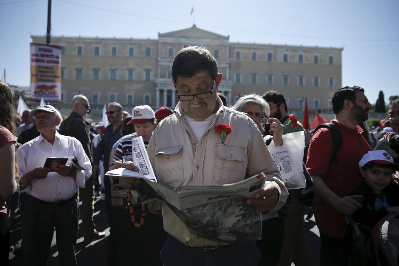 Un hombre con un clavel en la solapa lee un diario ante el Parlamento griego, en Atenas (Reuters).