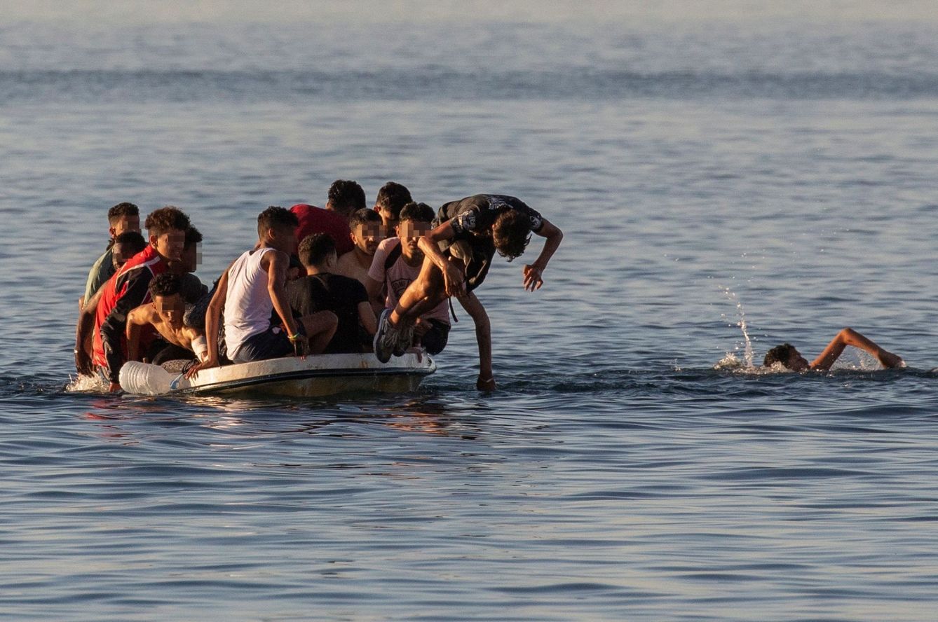 Varios menores migrantes se lanzan al agua para alcanzar la playa ceutí de El Tarajal. (EFE) 