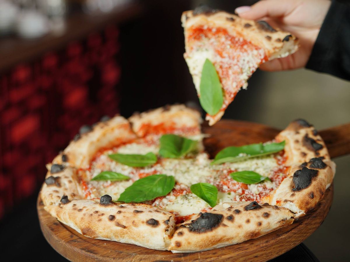 Foto: Una persona está cogiendo un trozo de pizza en un restaurante (Pexels)