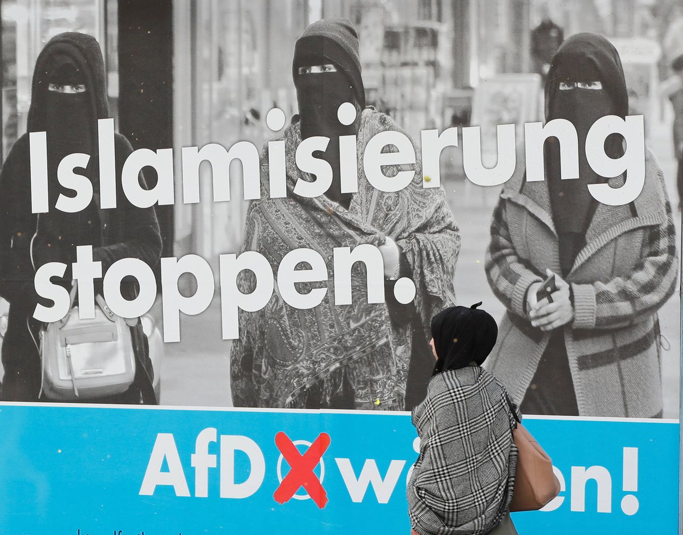 Una mujer musulmana pasa ante un cartel electoral de AfD, en Duisburg, Alemania. (Reuters)