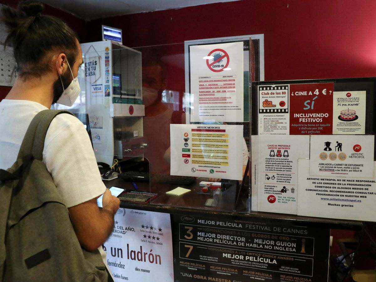 Foto: Un cliente, ataviado con mascarilla, lee las medidas de seguridad antes de entrar a una sala de cine. (EFE)