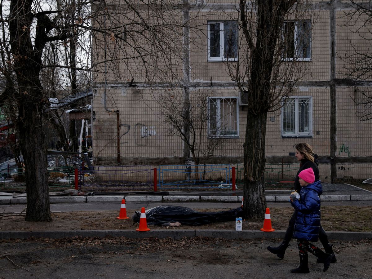 Foto: Una mujer pasea con su hijo frente a un fallecido en Kiev. (Reuters/Thomas Peter)