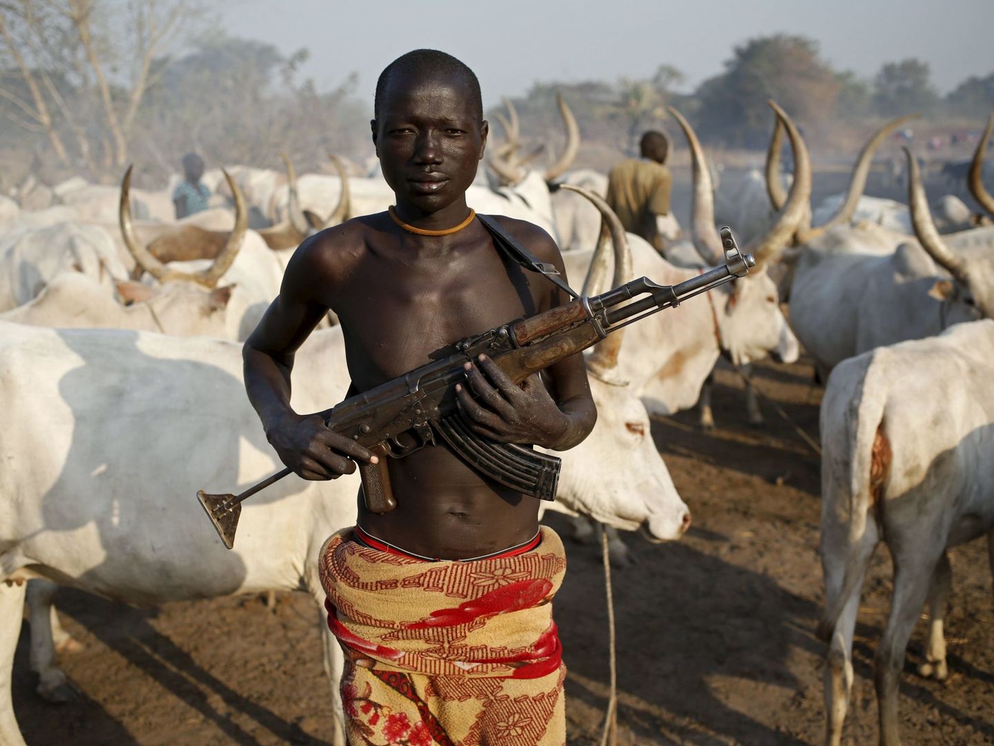 Un miembro de la tribu dinka sostiene su rifle AK47 ante un rebaño de vacas cerca de Rumbek, Sudán del Sur. (Reuters)