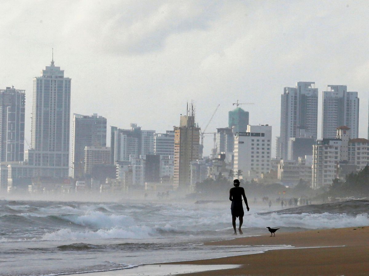 Foto: Un hombre pasea en una playa de Sri Lanka, con la ciudad financiera de Colombo al fondo. (Reuters/Dinuka Liyanawatte)