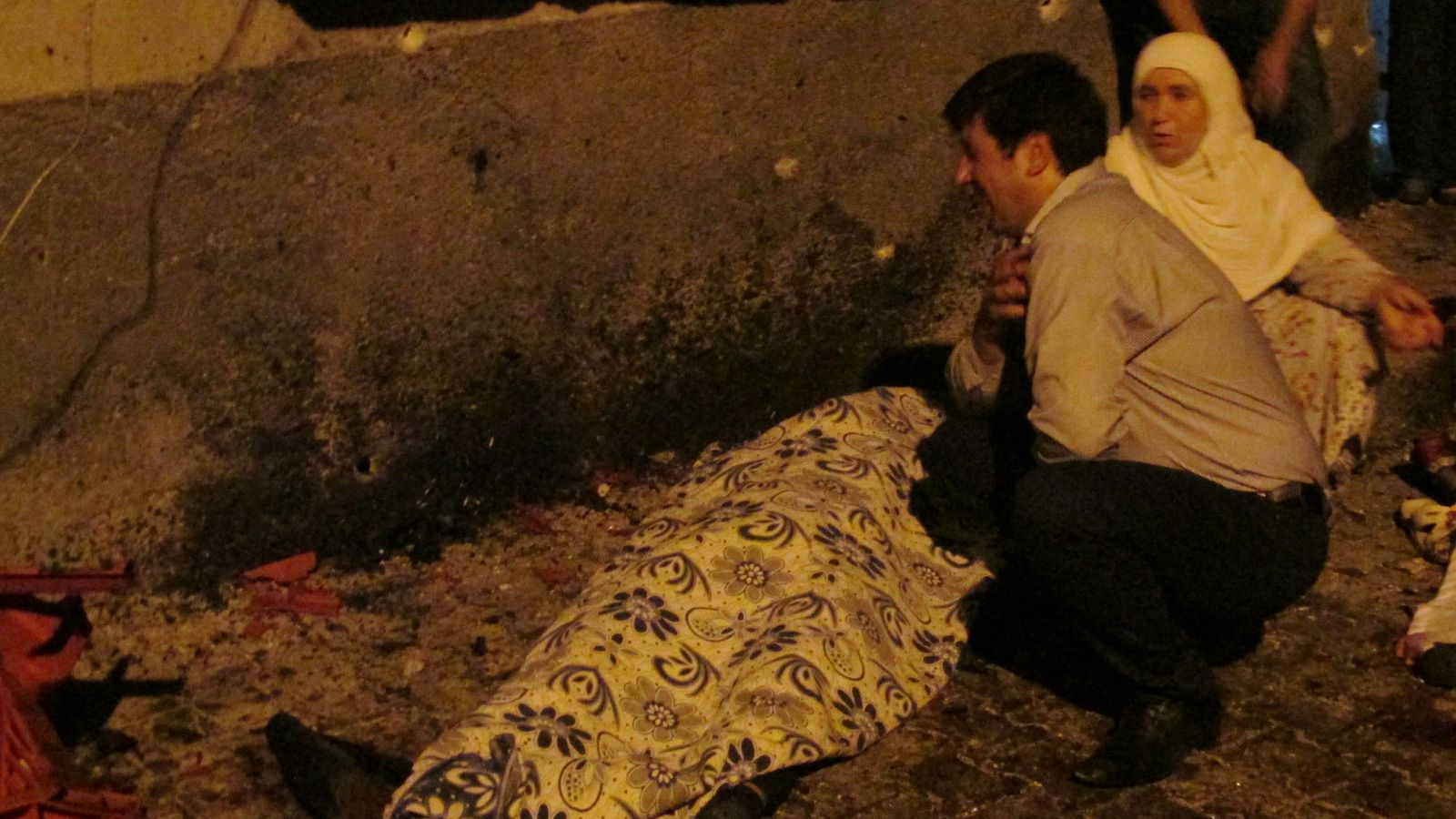 Foto: Un hombre y una mujer junto a un cuerpo de una víctima. (Reuters)