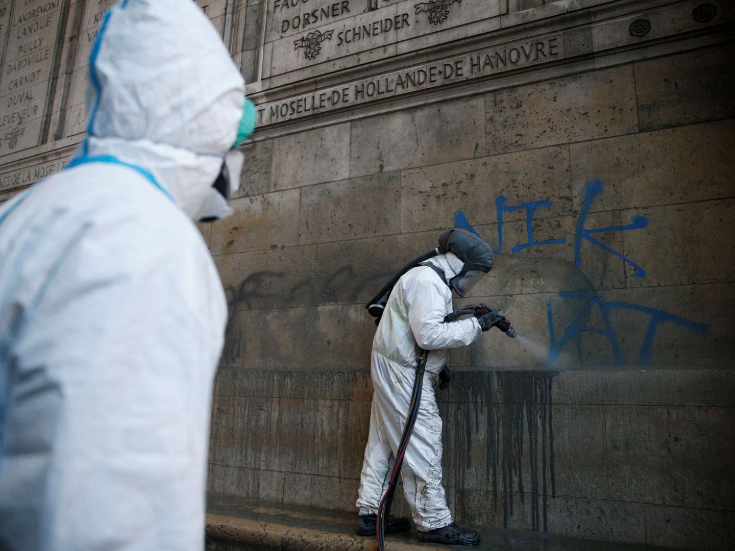 Equipos de limpieza trabajan para eliminar las pintadas de la base del Arco de Triunfo. (Reuters)
