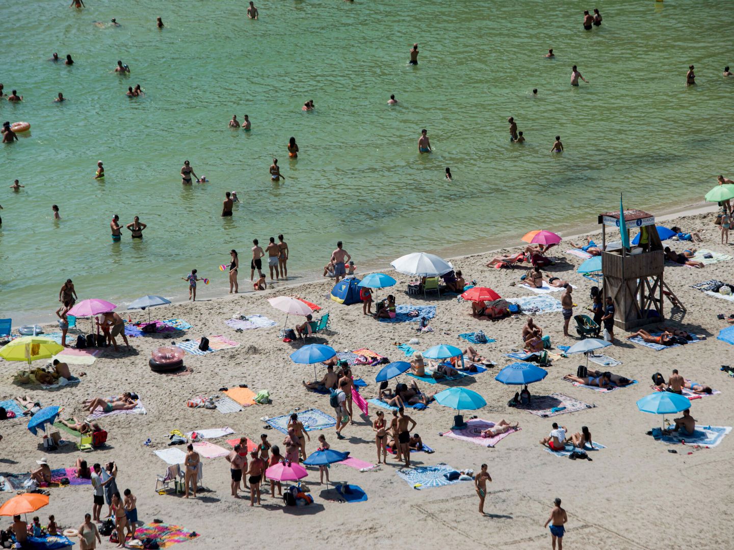 Los bañistas intentan paliar el calor de este viernes en la playa de Cala en Porter, en la isla de Menorca. (EFE/D. Arquimbau)