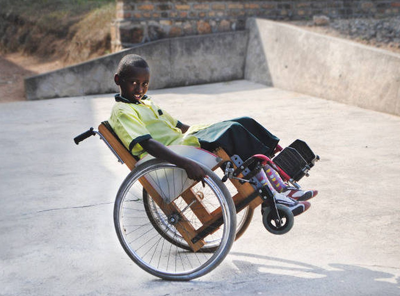 Un niño aprende a manejar su silla de ruedas. (Kigali Chair Project)