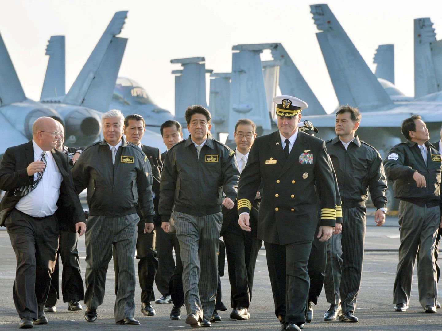 Shinzo Abe (c), primer ministro de Japón, junto al responsable de Defensa nipón (2i) y el capitán del USS Ronald Reagan en la bahía de Sagami, en 2015. (Reuters)