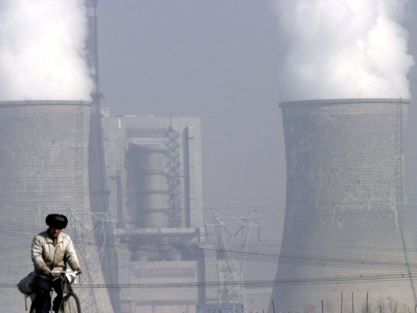 Un ciclista circula junto a una central de carbón en China (EFE/ Qilai Shen)