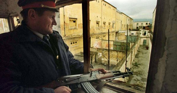 Foto: Un policía albanés vigila desde el tejado la principal cárcel de Tirana, en abril de 1997, durante los días del desplome del Gobierno de Sali Berisha. (Reuters)