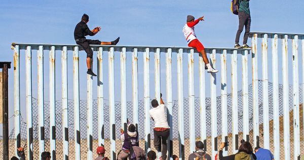 Foto: Integrantes de la caravana de centroamericanos escalan el muro fronterizo en Tijuana. (EFE)