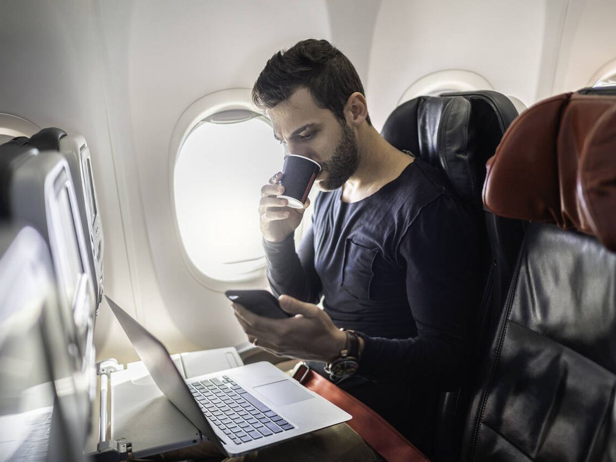 Foto: Un chico bebiendo café en un avión (iStock)