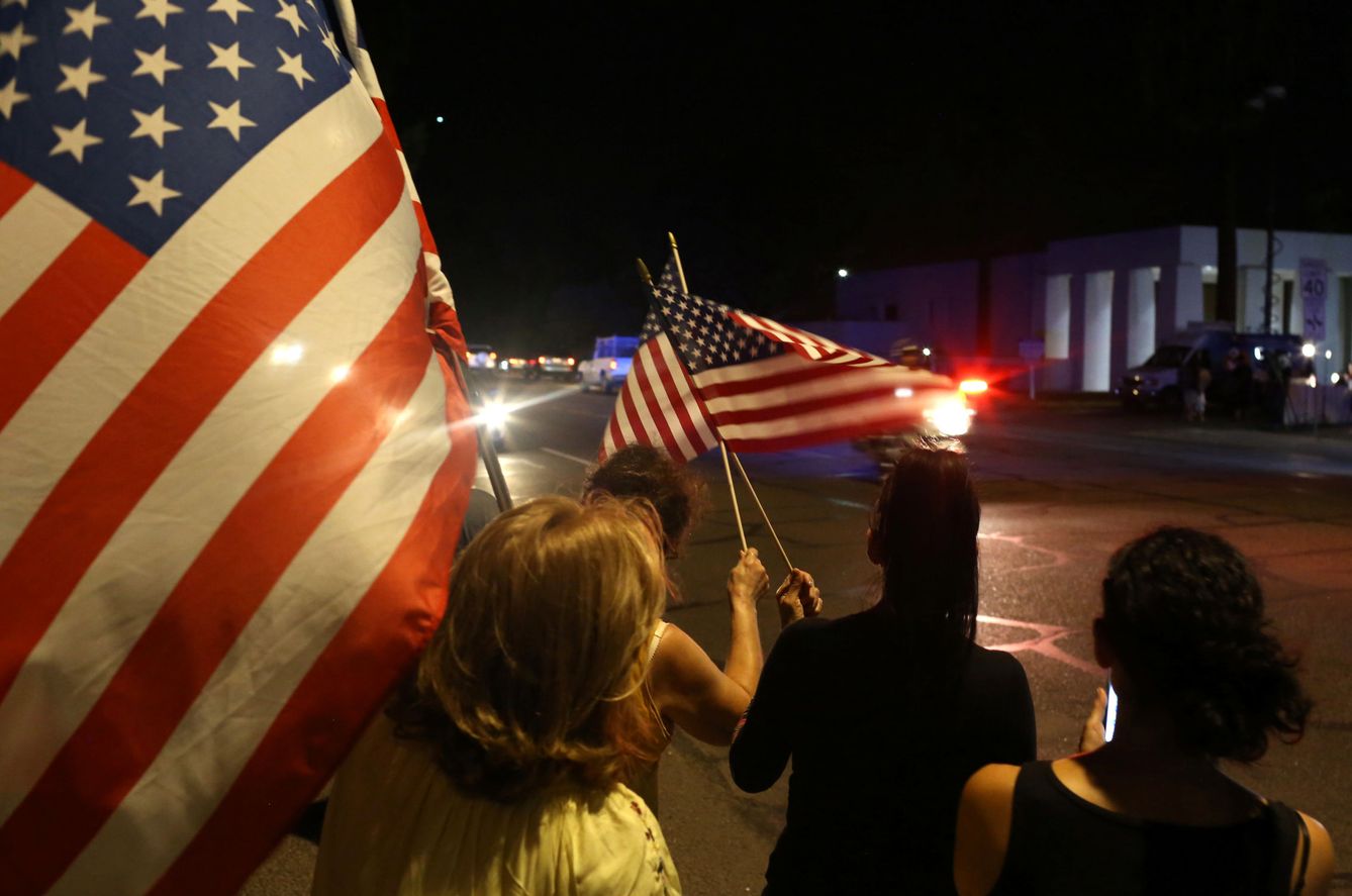 Decenas de personas han salido a la calle con banderas al paso del coche fúnebre con el cuerpo de McCain. (Reuters)