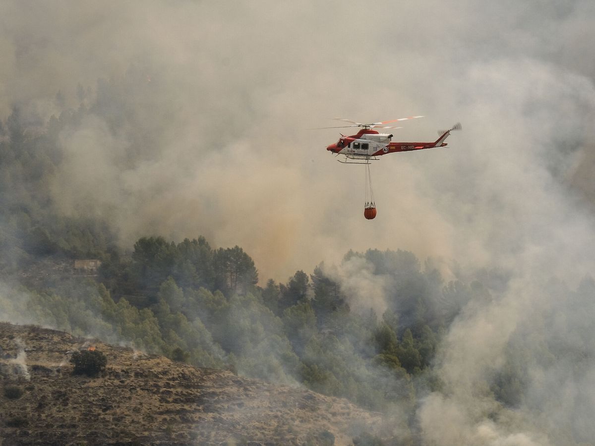 Foto: Un helicóptero de los Servicios de Emergencia trabaja en la extinción del incendio forestal de Tárbena. (EFE/Pablo Miranzo)