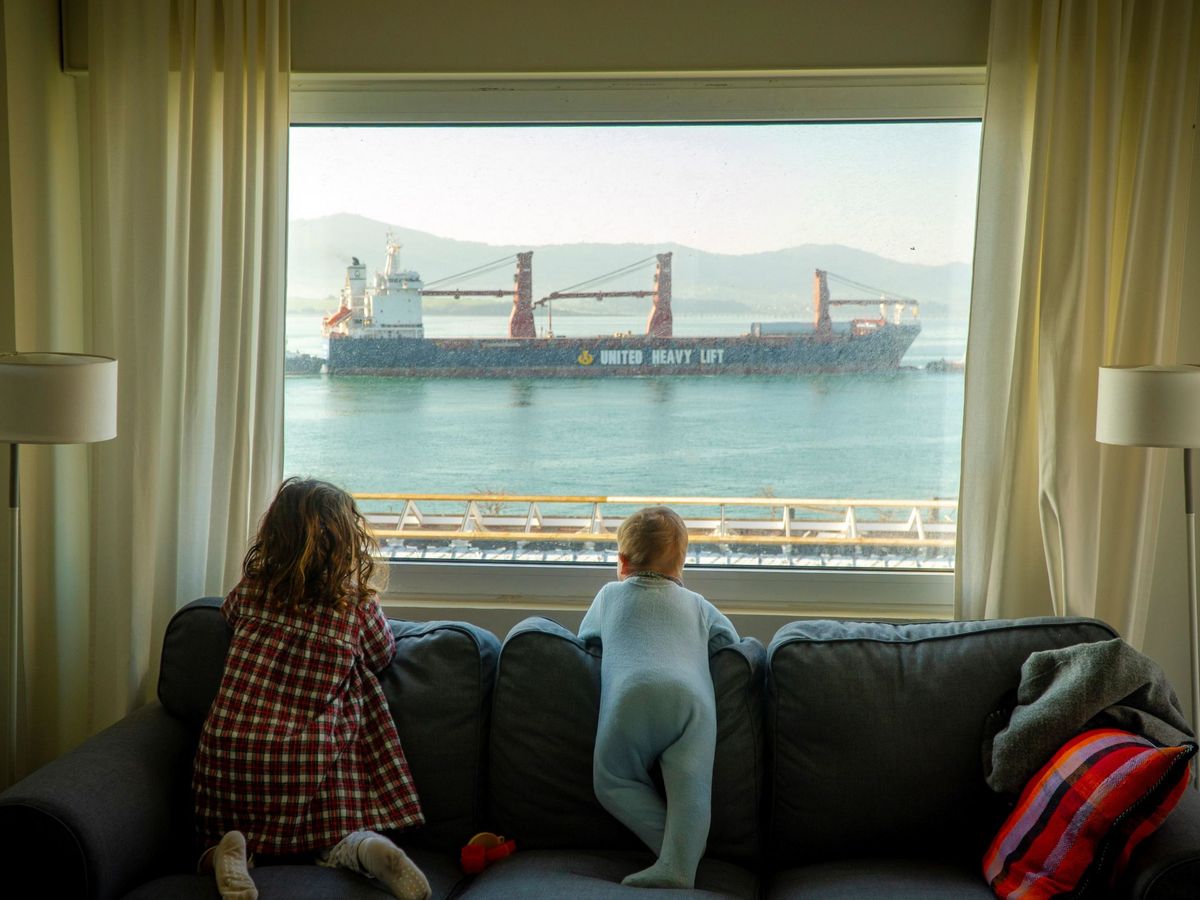 Foto: Dos niñas observan desde casa la entrada de barcos mercantes en la bahía de Santander, durante el 11º día de confinamiento, el pasado 25 de marzo. (EFE)