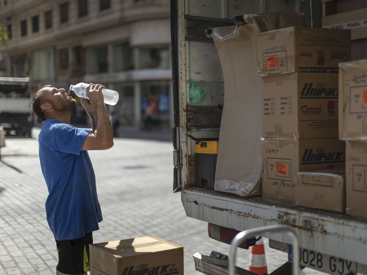 Foto: Un trabajador de una empresa de mudanzas bebe agua para combatir el calor en una calle del centro de Valencia. (EFE)