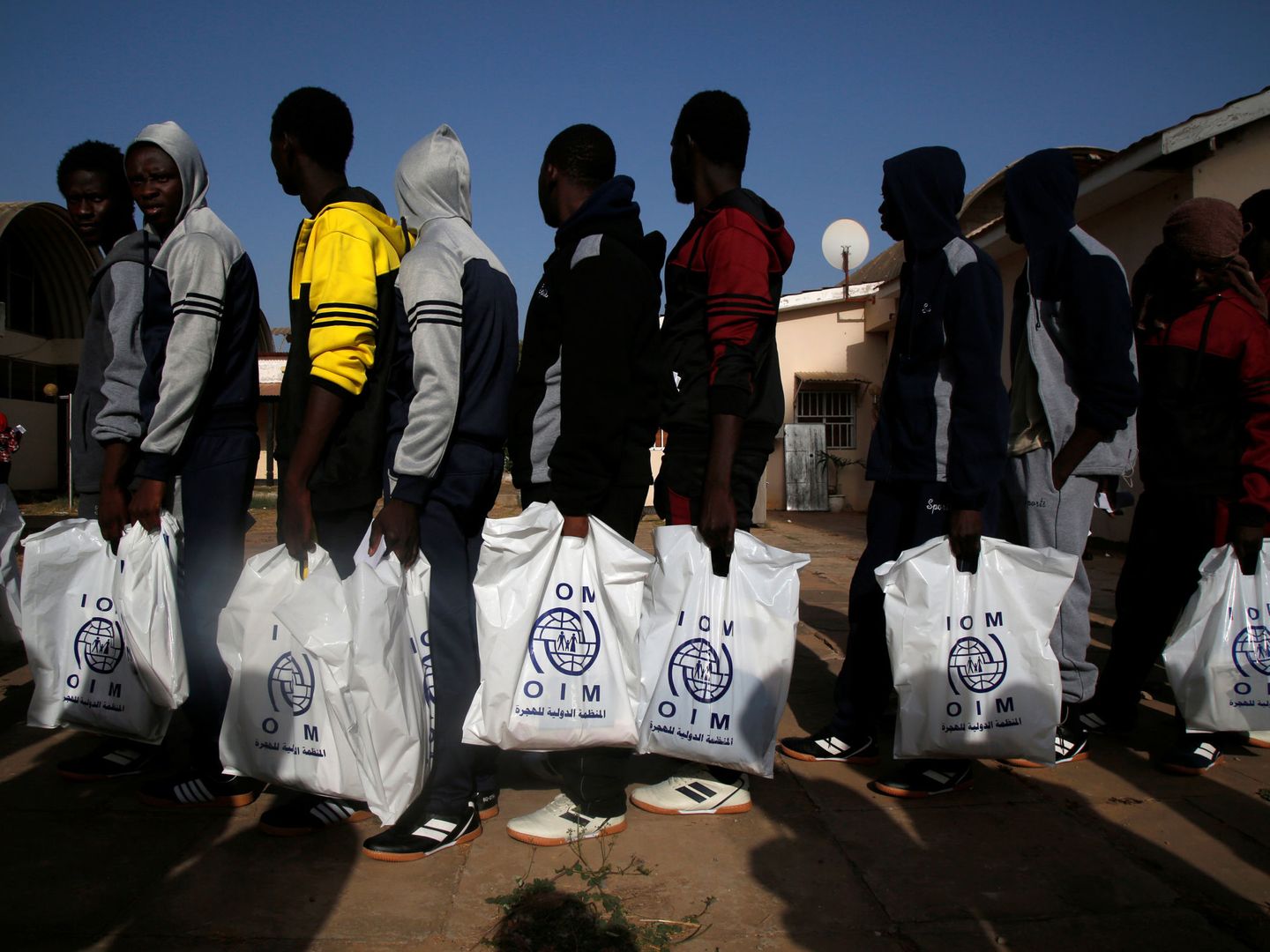 Inmigrantes de Gambia deportados de Libia hacen cola en el aeropuerto de Banjul. (REUTERS)