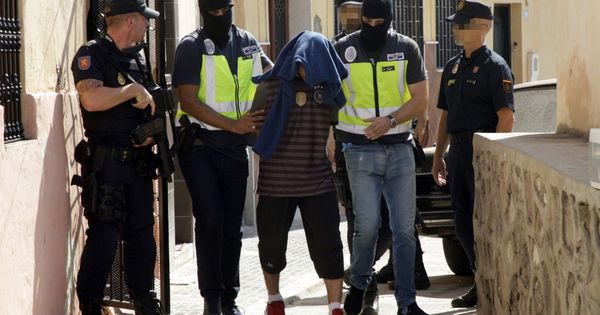 Foto: Efectivos de la Policía Nacional trasladan a Hafid Mohamed, detenido durante el registro realizado en el domicilio del barrio periférico del Monte María Cristina de Melilla. (EFE)