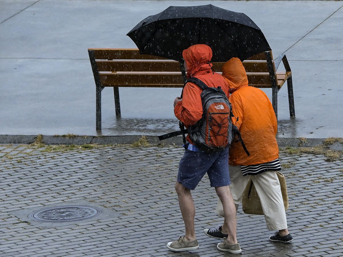 Foto: Dos personas paseando bajo la lluvia en A Coruña. Foto de archivo (EFE/Moncho Fuentes)