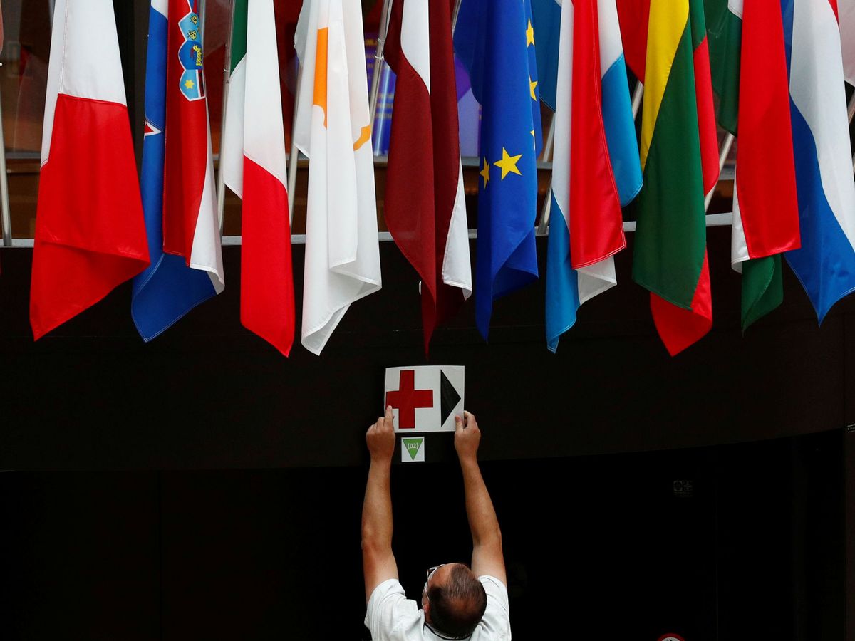Foto: Un empleado coloca una señal bajo las banderas europeas en el Consejo. (Reuters)