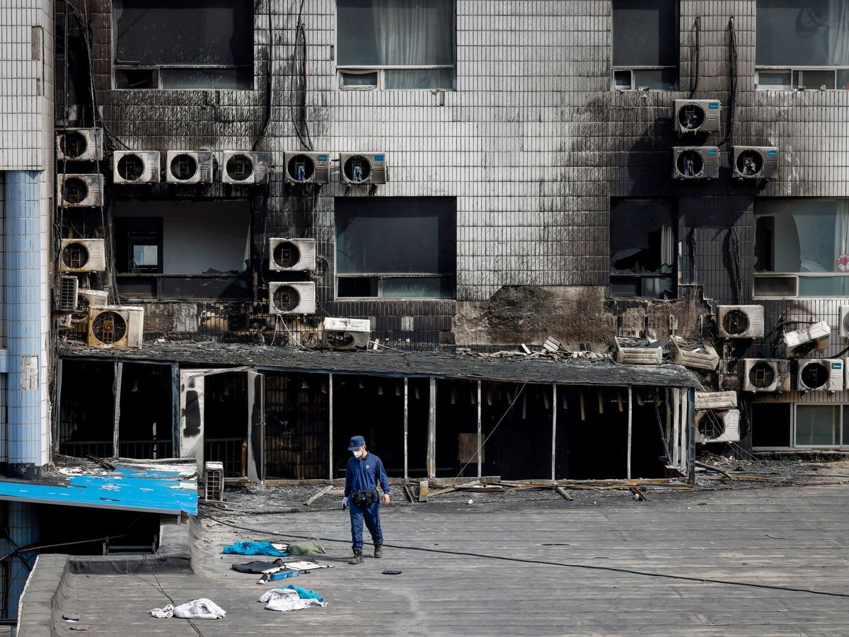Foto: Un investigador camina entre ropas y pertenencias tras el incendio en el hospital Changfeng de Pekín. (EFE/EPA/Mark R. Cristino)