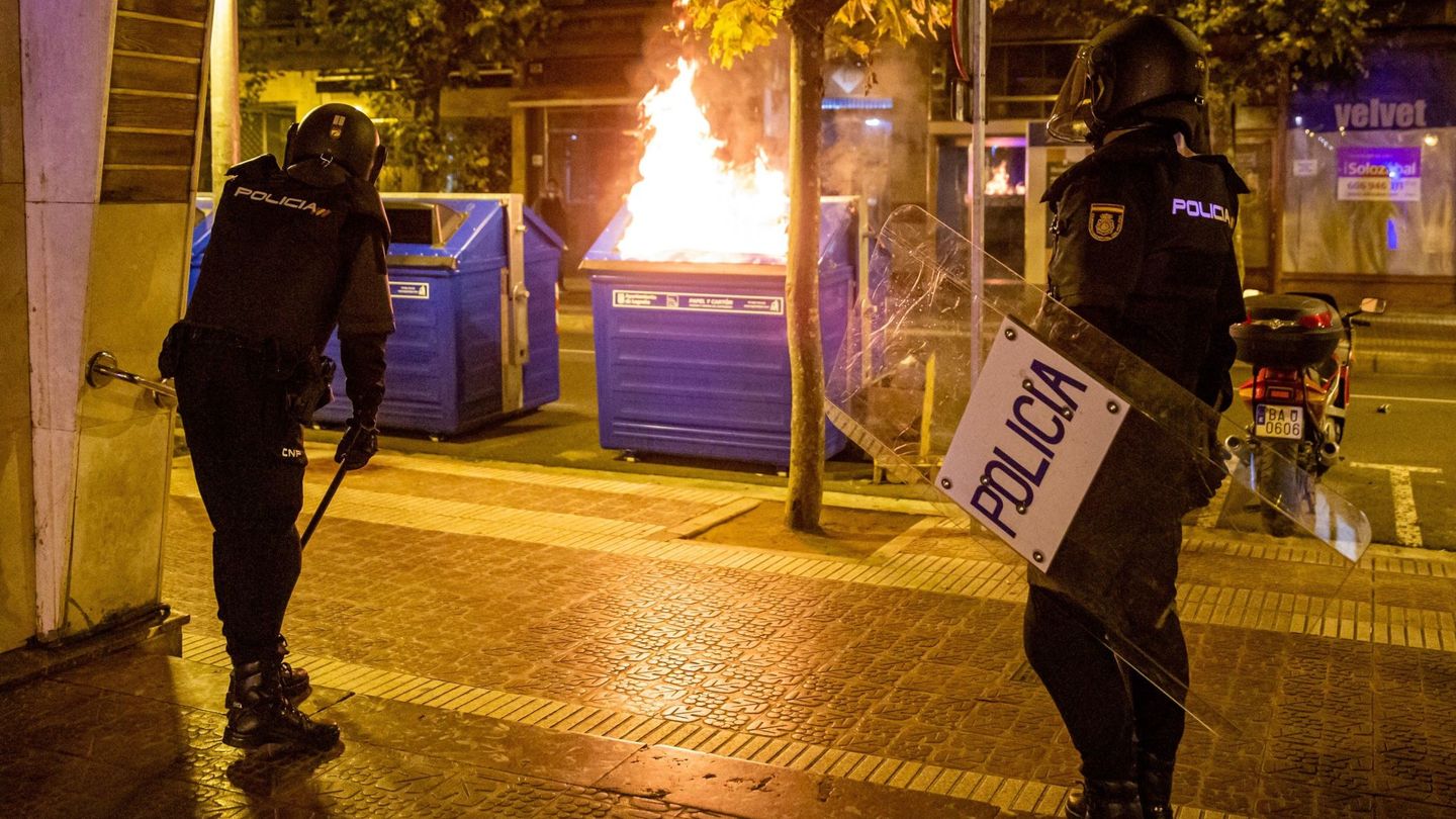 Agentes de la Policía, junto a un contenedor de papel que arde en Logroño. (EFE)