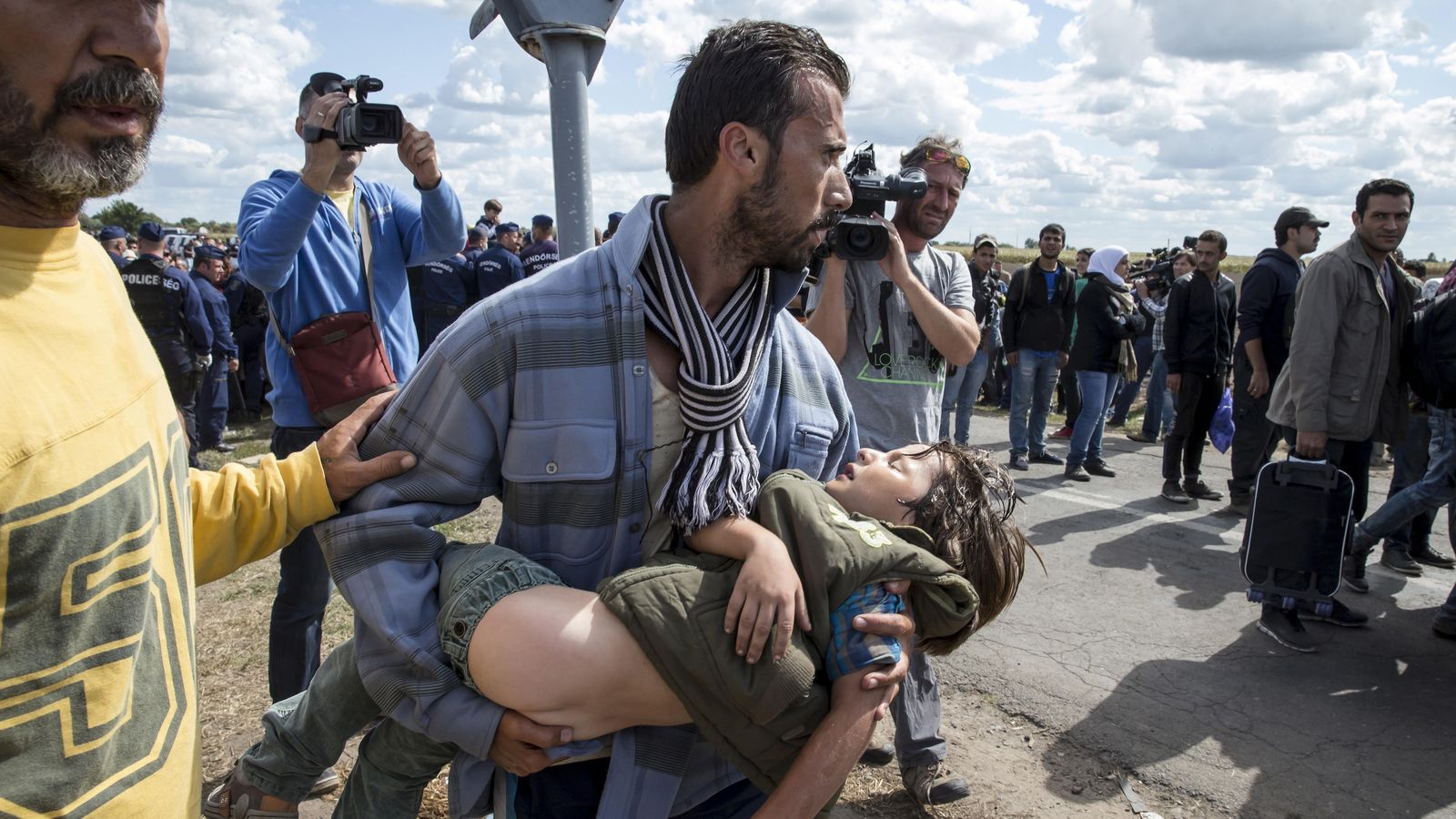 Foto: Un refugiado carga con su hijo enfermo cerca del punto de control en Roszke (Hungría). (Reuters)