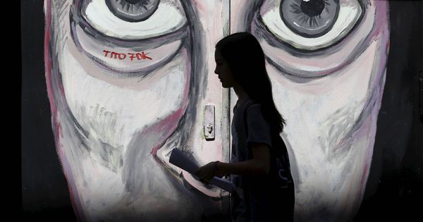 Foto: Una mujer pasa por delante de un grafiti en el barrio de Malasaña, en Madrid. (Reuters)