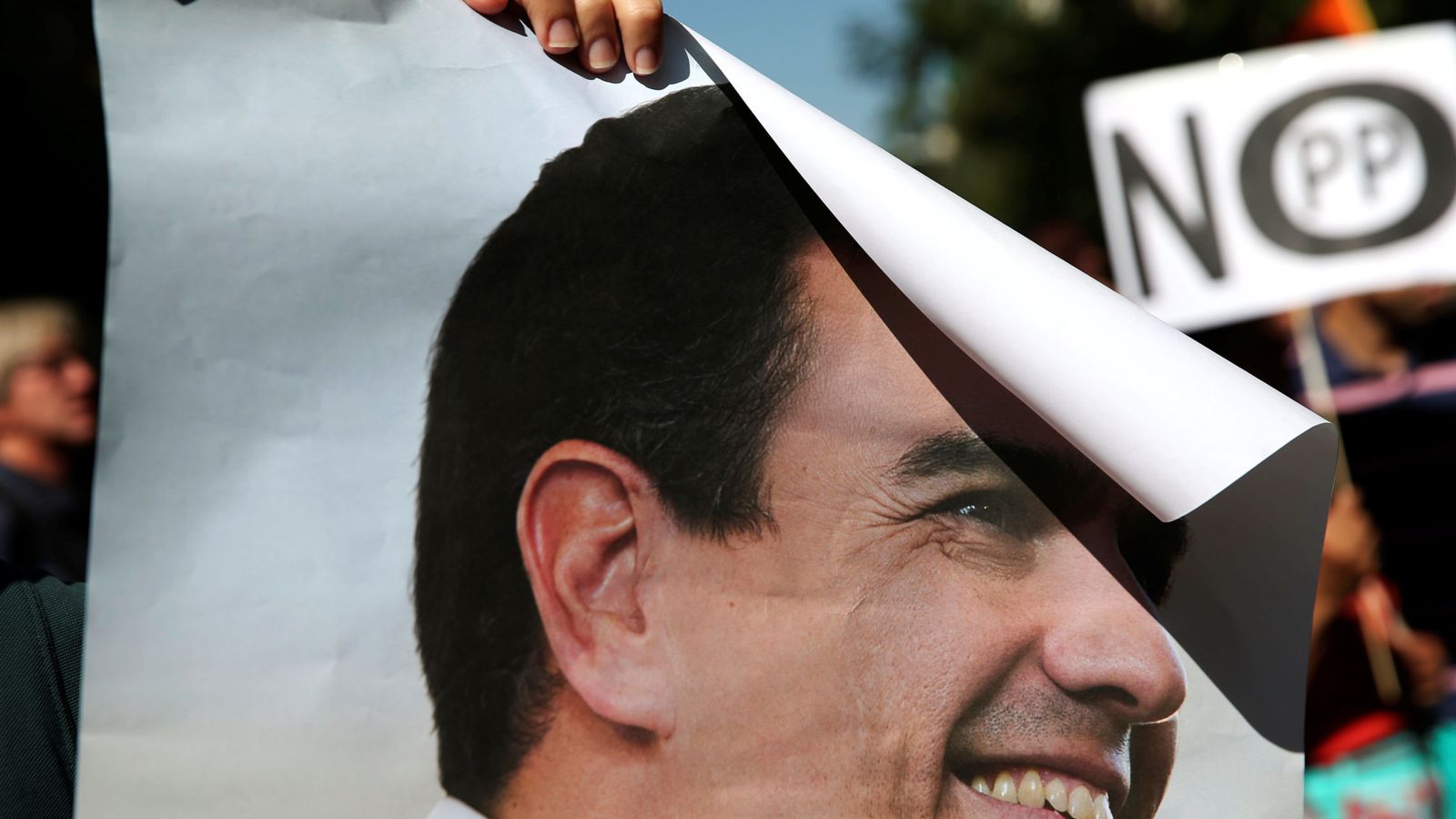 Foto: Un manifestante sostiene un cartel de Pedro Sánchez y otro uno de 'No al PP', el pasado 1 de octubre en Ferraz, mientras se celebraba el comité federal del PSOE. (Reuters)