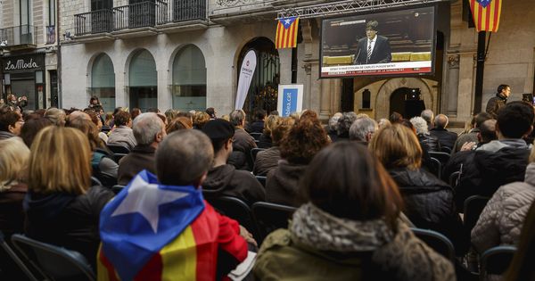 Foto: Ciudadanos de Girona sigueindo la investidura de Puigdemont en pantalla grande. (EFE) 