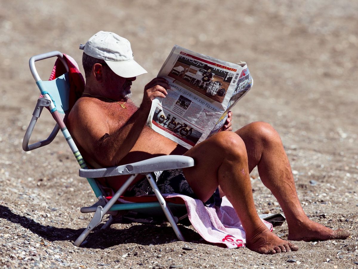 Foto: Una persona leyendo el periódico en la playa de la Malagueta. (EFE/Jorge Zapata)