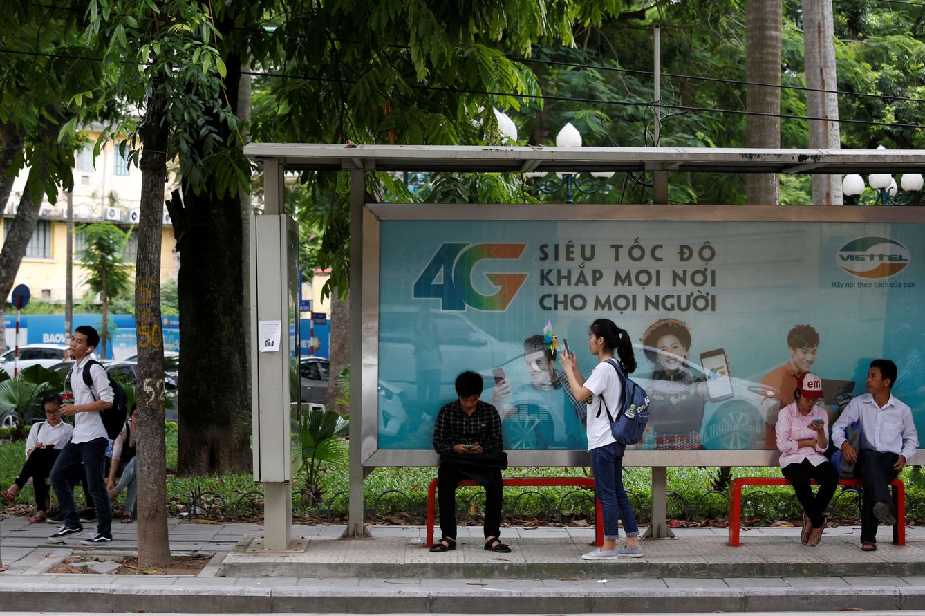 Usuarios de internet se conectan con sus móviles frente a un anuncio de conectividad 4G en una parada de autobús en Hanoi, en agosto de 2017. (Reuters)