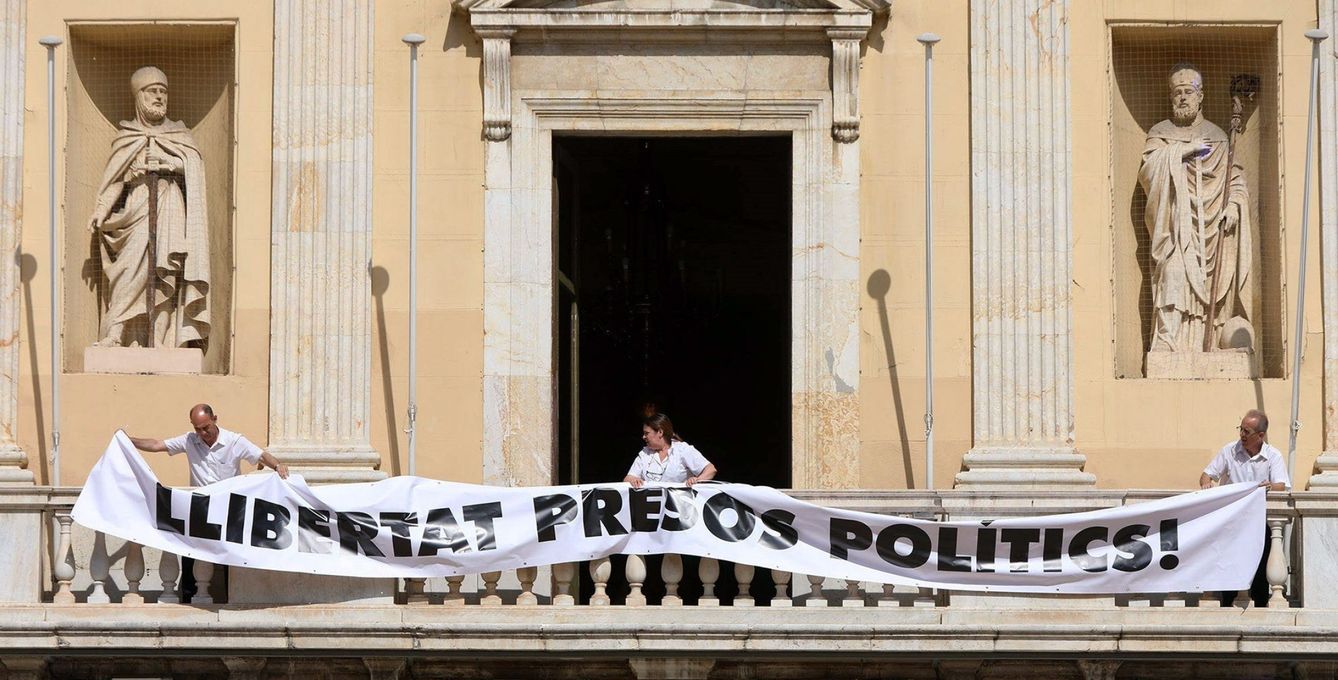Operarios del Ayuntamiento de Tarragona cuelgan la pancarta. (EFE)