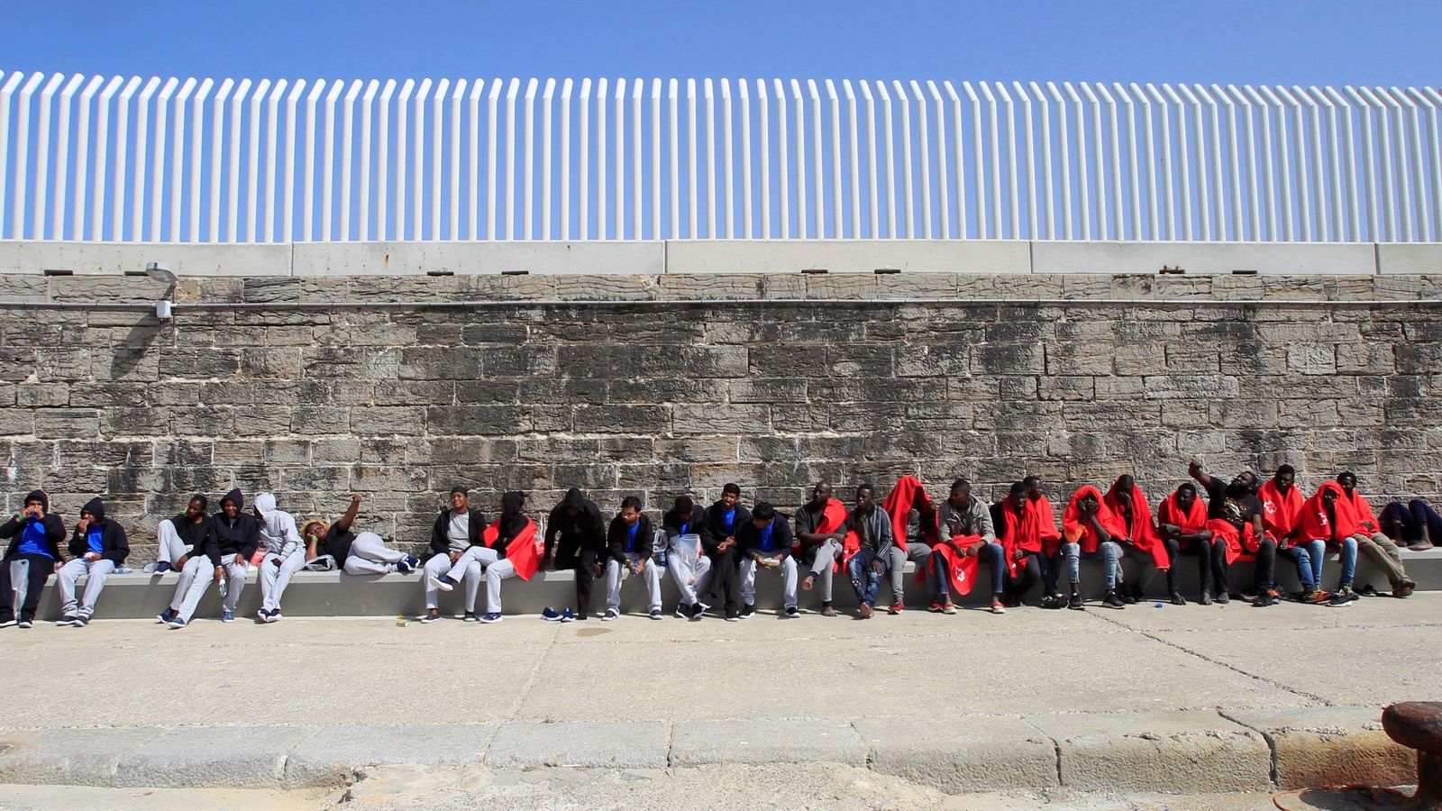 Foto: Inmigrantes esperan en el puerto de Tarifa (Cádiz) a ser trasladados por la Guardia Civil tras ser atendidos por Cruz Roja. (EFE)