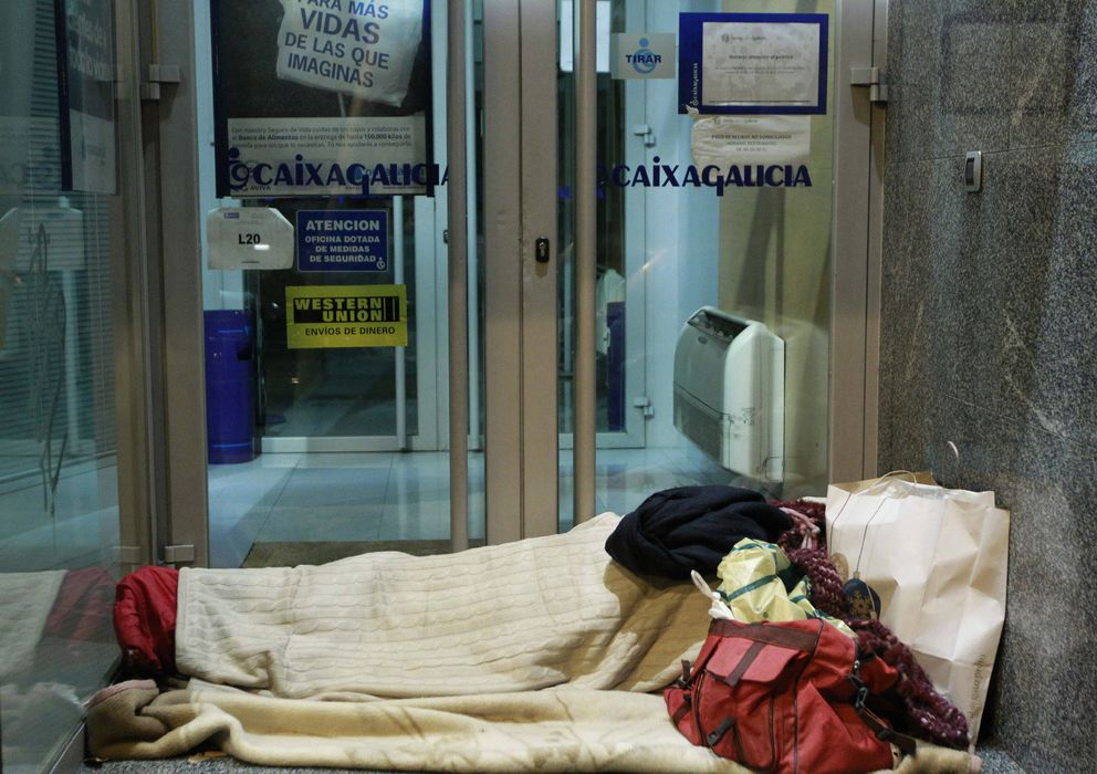 Foto: Un indigente se dispone a pasar la noche a las puertas de una entidad bancaria. (EFE)