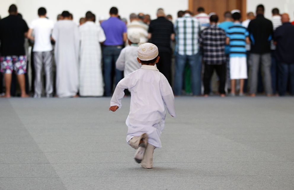 Dos niños corren hacia un grupo de fieles que rezan en la mezquita de Estrasburgo, Francia (Reuters).