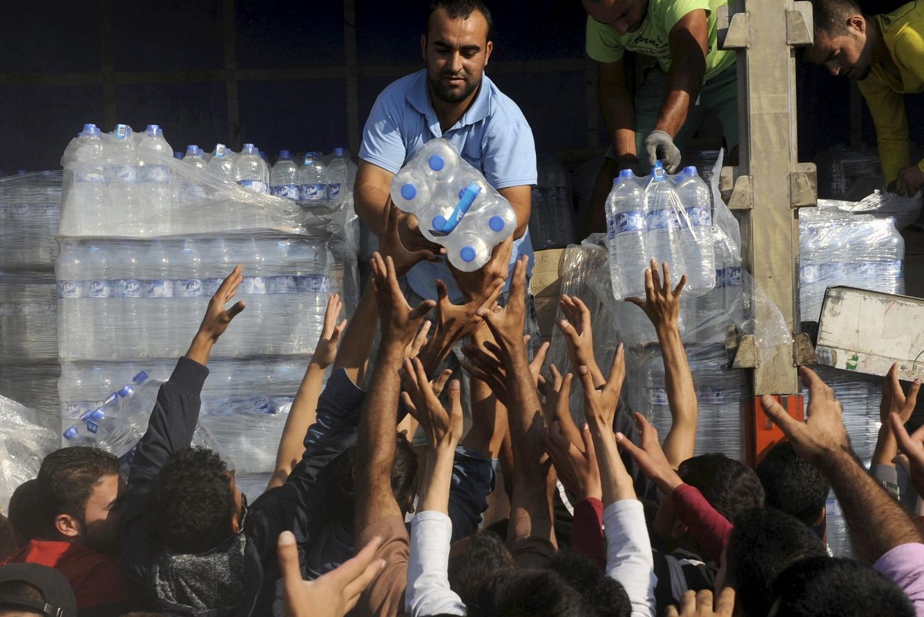 Foto: Refugiados reciben botellas de agua cerca de la frontera griega, en el pueblo de Idomeni (Reuters).
