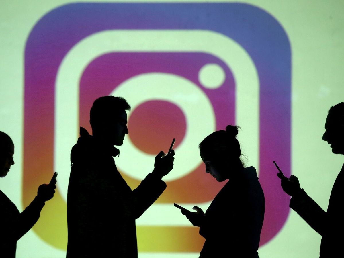 Foto: Varias personas consultan sus teléfonos frente a una proyección del logo de Instagram. (Reuters/Dado Ruvic)
