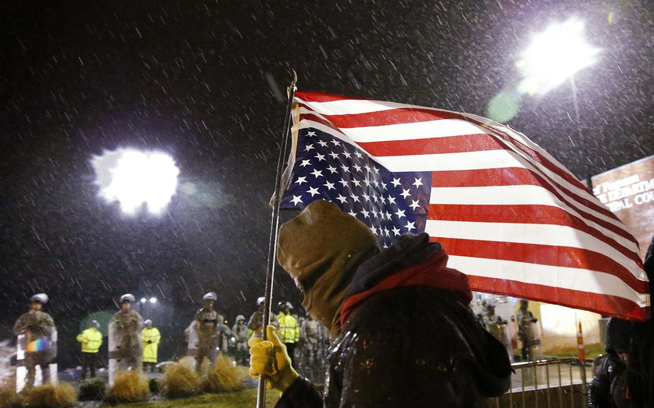 Un manifestante con una bandera de EEUU boca abajo durante una protesta en Ferguson (Reuters).