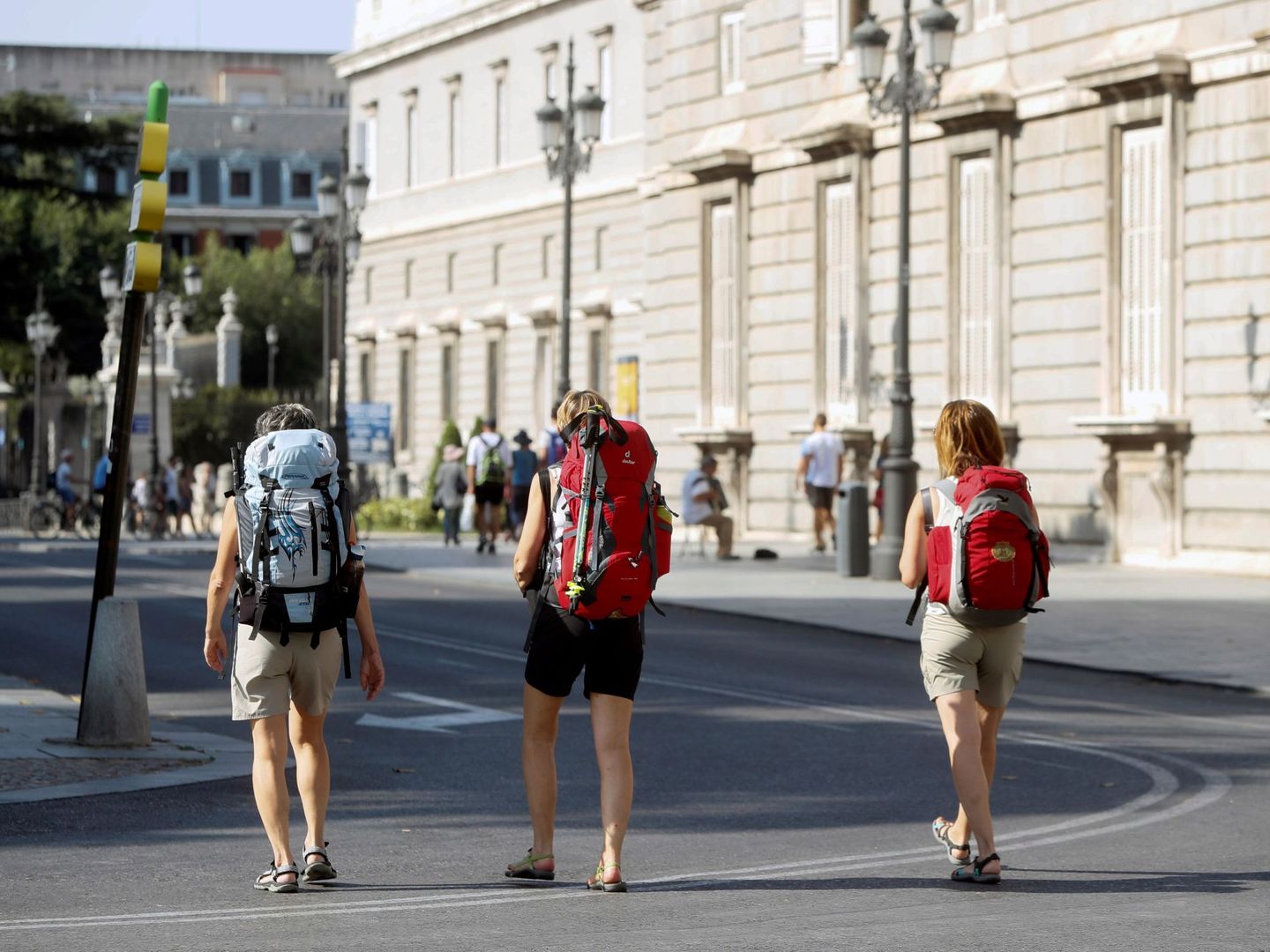 Turistas cargadas con sus mochilas pasean por las inmediaciones del Palacio Real de Madrid. (EFE)