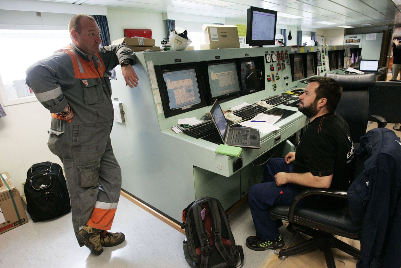 Dos trabajadores en la sala de control de carga y descarga del buque. (EFE)