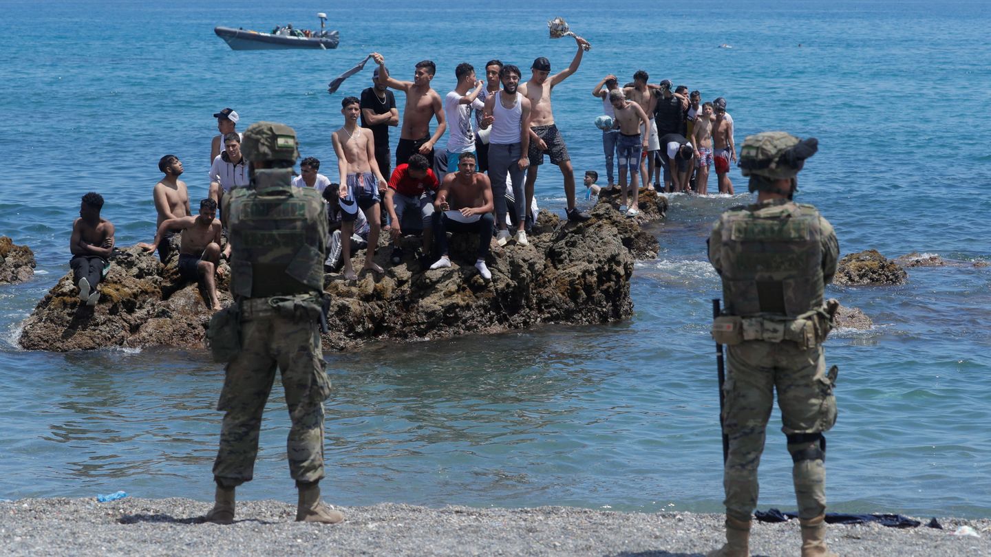 Dos efectivos del Ejército de España ante unos jóvenes marroquíes que han cruzado a nado hasta Ceuta. (Reuters)