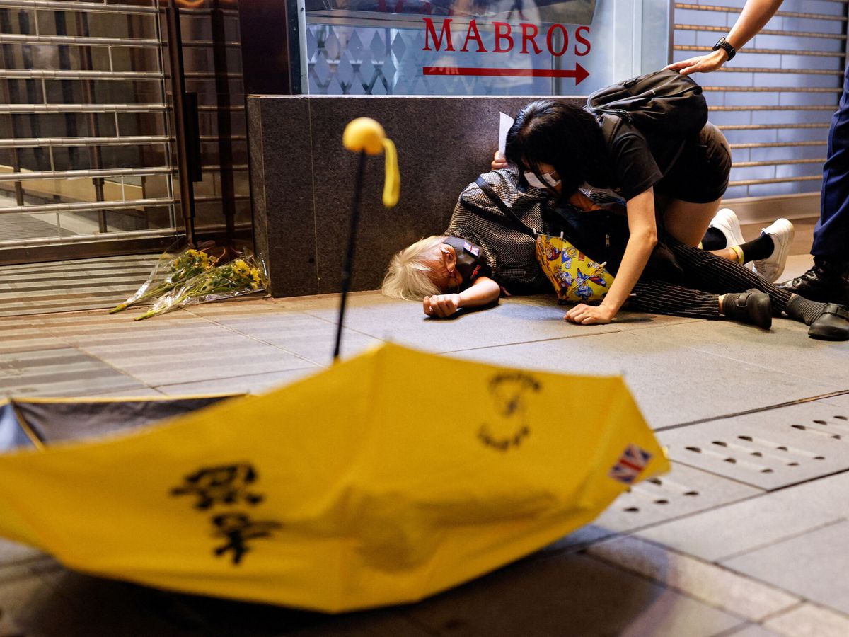 Foto: Dos personas caen al suelo durante las manifestaciones antirrestricciones covid en China. (Reuters/Tyrone Siu)
