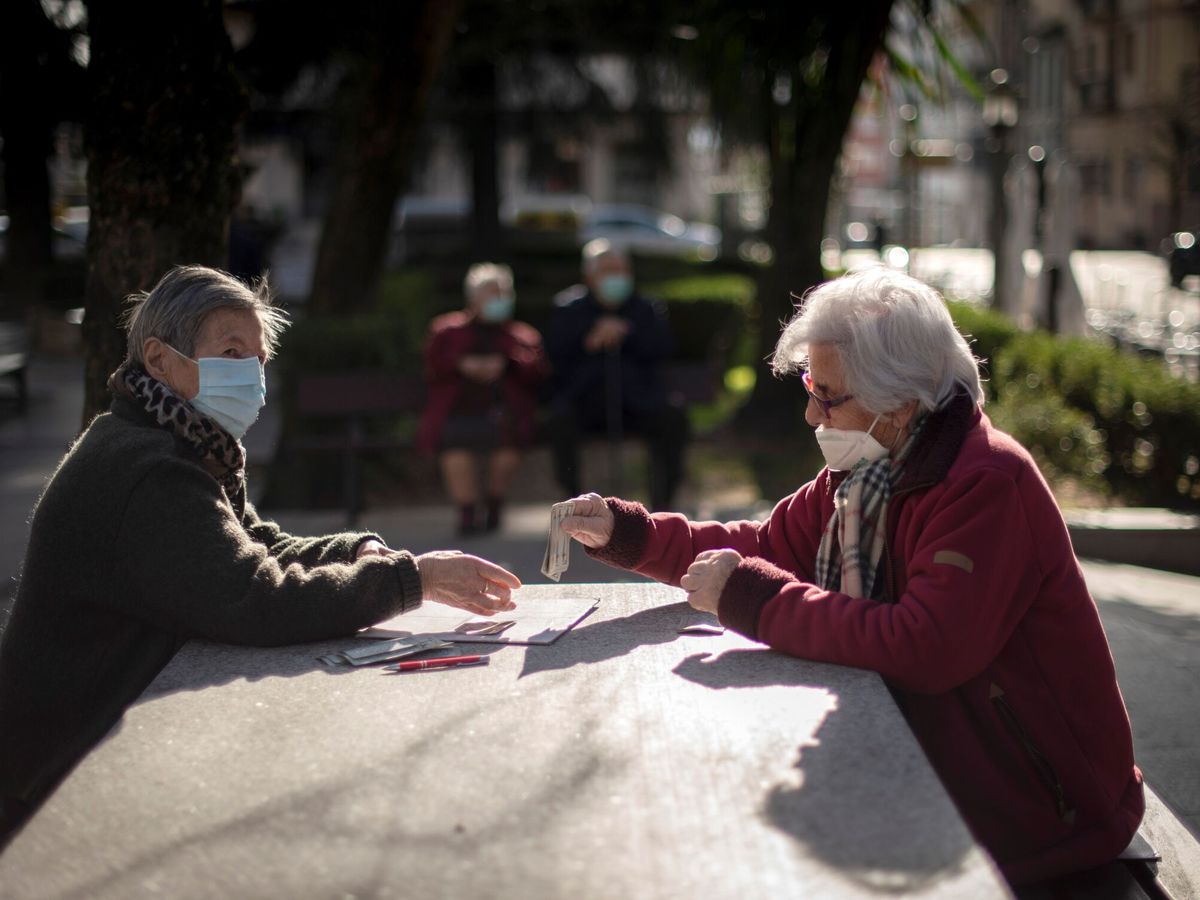 Foto: Dos mujeres con mascarillas juegan a las cartas en un parque de Ourense. (EFE/Archivo/Brais Lorenzo)