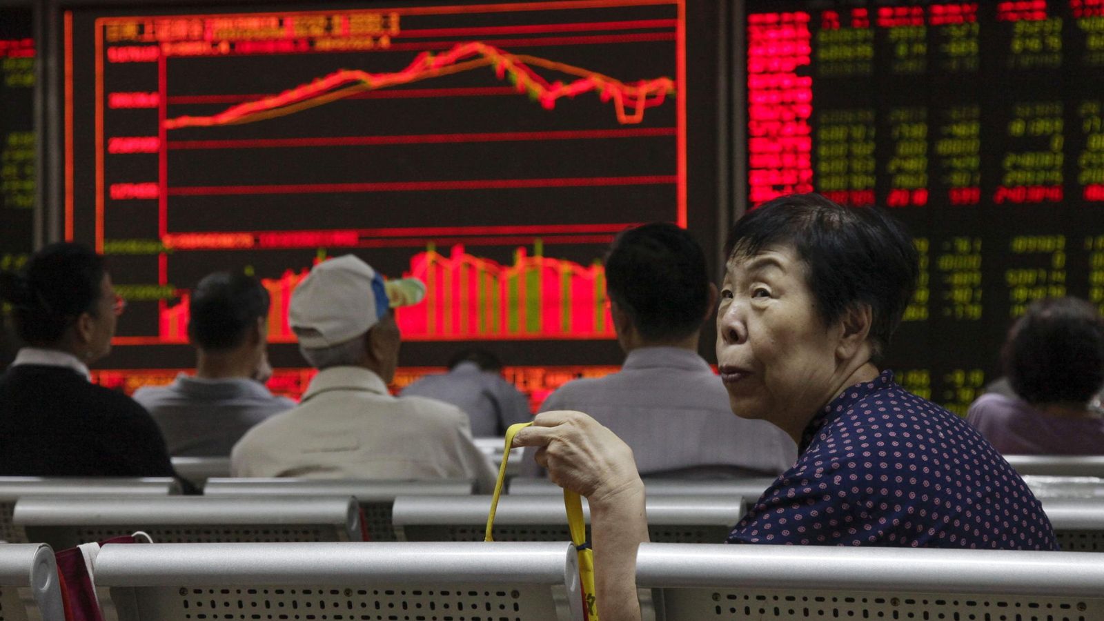 Foto: Varios inversores chinos sentados delante de una pantalla que muestra información bursátil. (EFE)