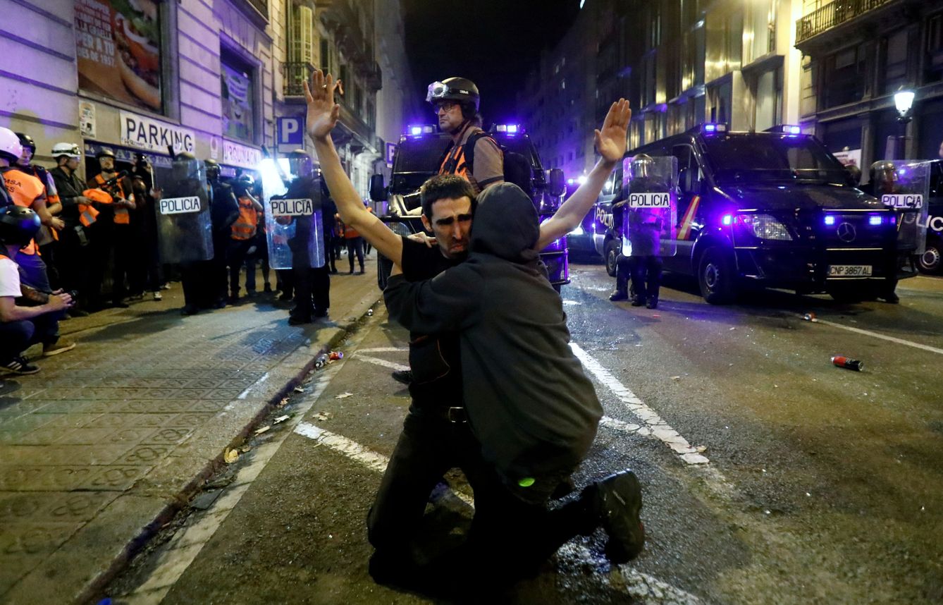 Un manifestante catalán recibe un abrazo mientras se arrodilla en el suelo durante la protesta del sábado. (Reuters)